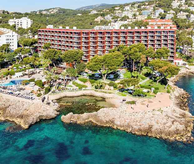 Luftfoto av en luksusresort ved kysten med omkringliggende natur og bassengområder. (AI-generert tekst)