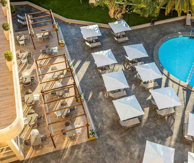 Utsikt ovenfra av et utendørsbasseng, bord med parasoller og sitteplasser. (AI-generert tekst)