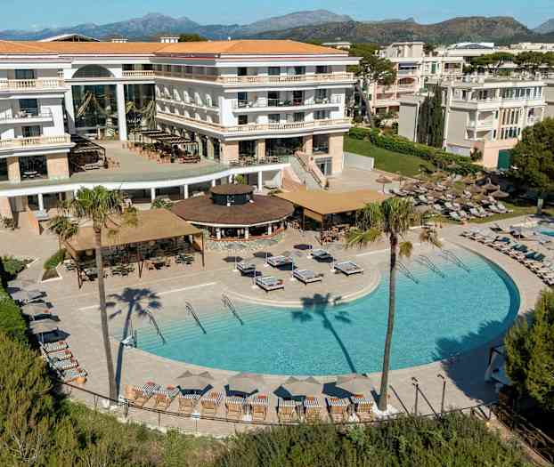 Hotell med basseng- og terrasseområde omgitt av solsenger, parasoller og grøntområder. (AI-generert tekst)