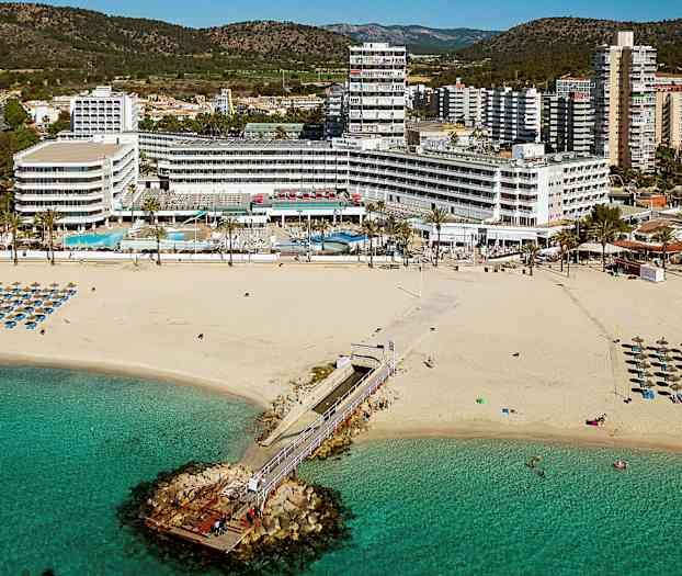 Bilde av en sandstrand med solsenger og parasoller, en brygge som fører ut i havet, og hotellbygninger i bakgrunnen. (AI-generert tekst)