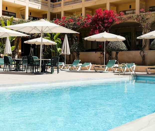 Et hotellbasseng med solsenger og parasoller. (AI-generert tekst)