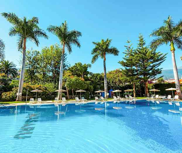 Bilde av et utendørs svømmebasseng omgitt av solsenger, parasoller og palmer. (AI-generert tekst)