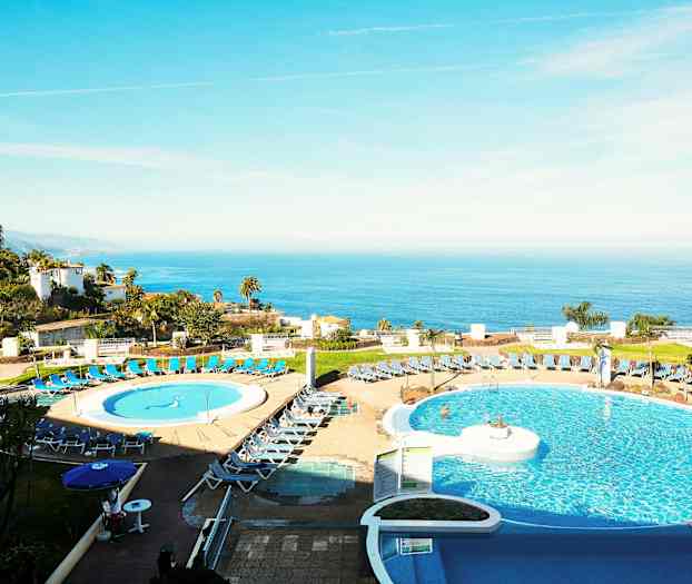 Bilde av et hotell med bassengområde i forgrunnen og havutsikt i bakgrunnen. (AI-generert tekst)