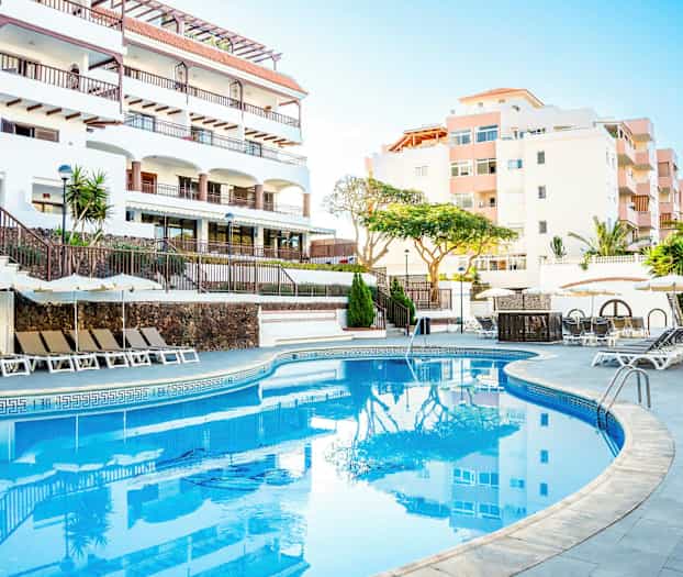 Utendørsbasseng med solsenger og parasoller ved et hotell. (AI-generert tekst)