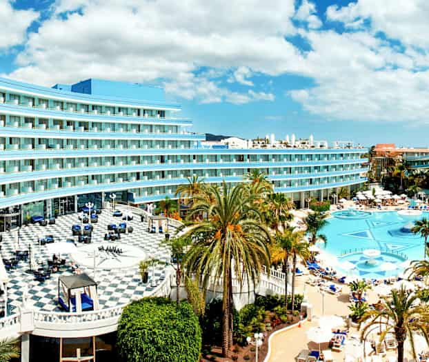 Bilde av hotell med basseng og palmer. (AI-generert tekst)