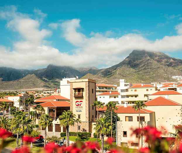 Utsikt over hotellområdet med fjell i bakgrunnen under en blå himmel. (AI-generert tekst)
