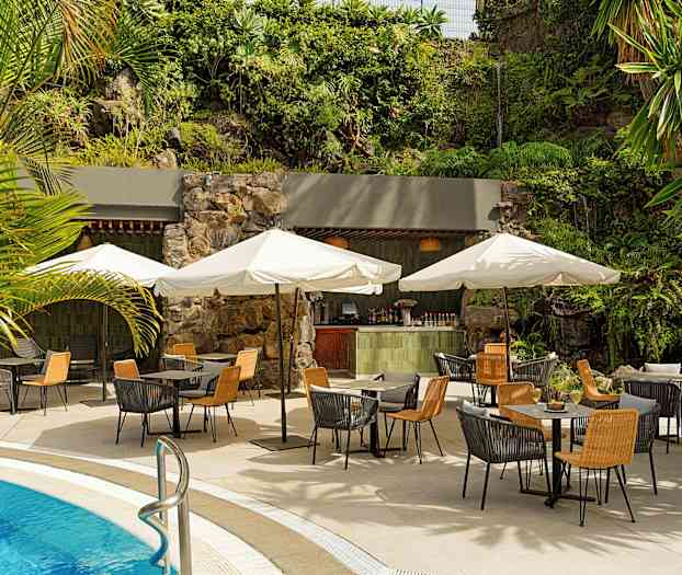 Utendørs servering ved bassenget med bord, stoler og parasoller. Bakgrunnen har grønn vegetasjon og en liten bar. (AI-generert tekst)