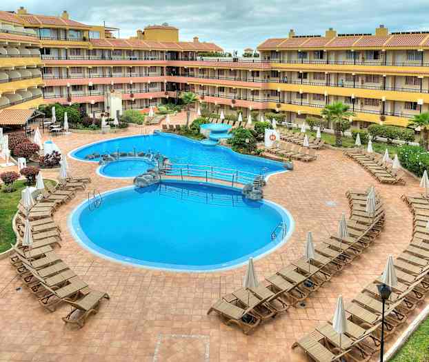 Et hotellbasseng omgitt av solsenger. (AI-generert tekst)