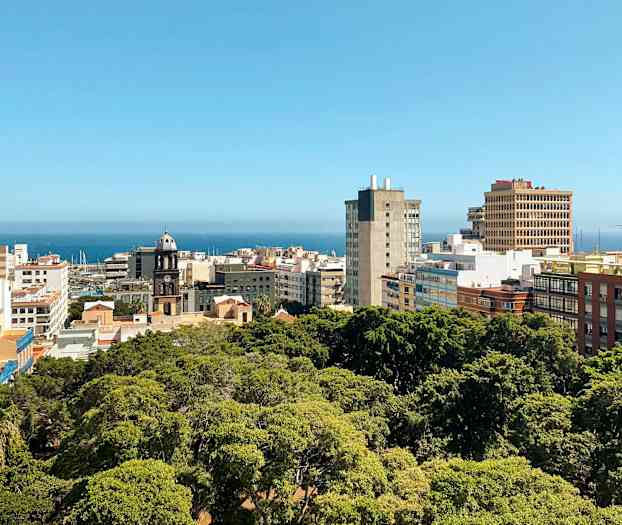 Byutsikt med bygninger og grøntområde, havet er synlig i bakgrunnen. (AI-generert tekst)