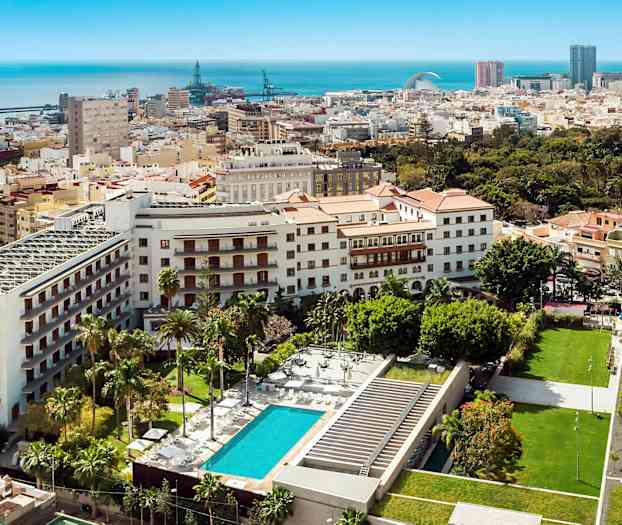 Utsikt over bymiljø med bygninger, grøntområder og basseng. (AI-generert tekst)