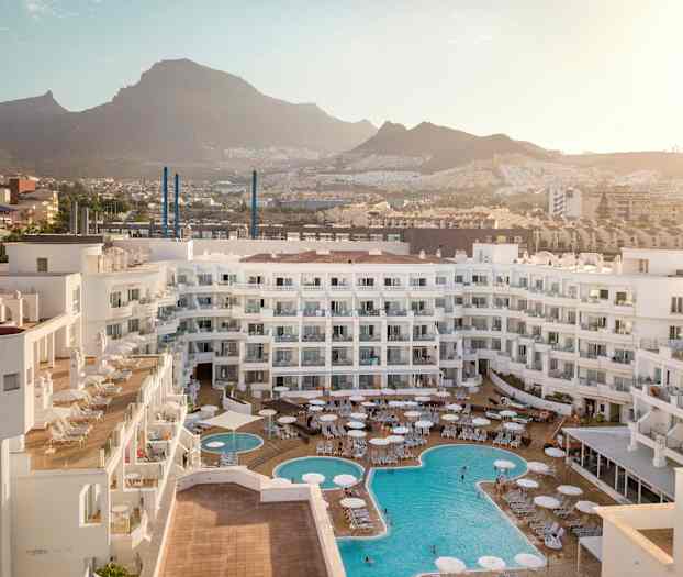 Utsikt over hotellområdet med bassenger og omkringliggende fjell. (AI-generert tekst)