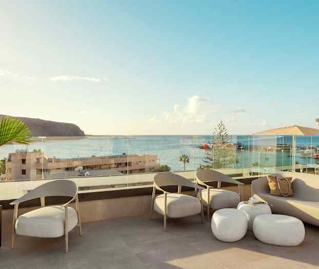 En terrasse med sitteplasser og utsikt over havet og en havn. (AI-generert tekst)