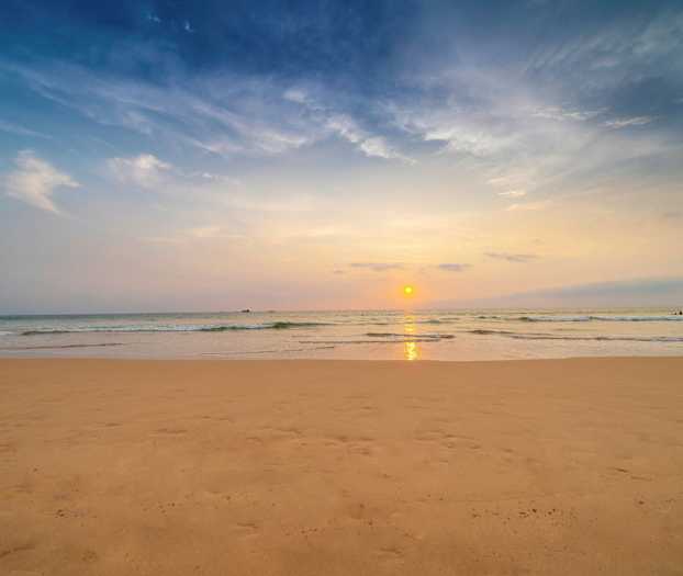 En strand ved solnedgang med havet i bakgrunnen. (AI-generert tekst)