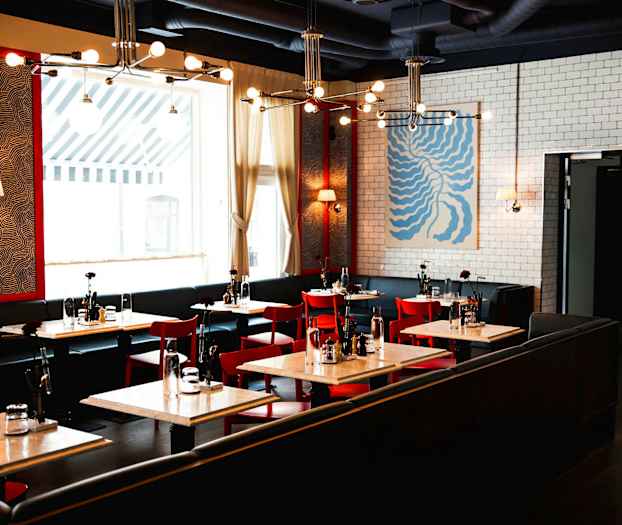 En moderne restaurant med røde stoler, hvite bord og vegger dekorert med kunst og mønstre. (AI-generert tekst)
