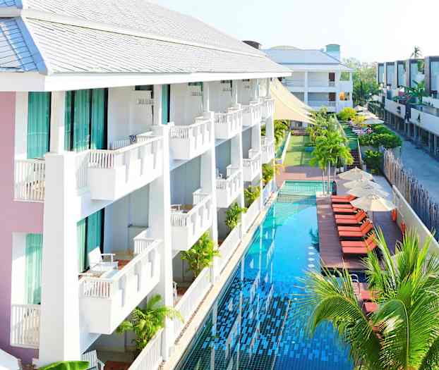 Et hotell med balkonger og et langt basseng ved siden av solsenger og parasoller. (AI-generert tekst)