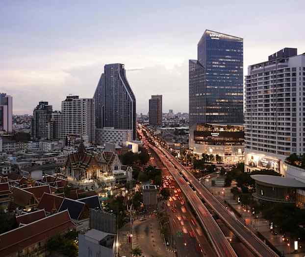 En skyline av en by med moderne skyskrapere, en travel vei og tradisjonelle bygninger i forgrunnen. (AI-generert tekst)