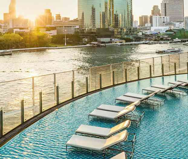 Et svømmebasseng på en høytliggende terrasse med utsikt over en elv i et urbant miljø. (AI-generert tekst)