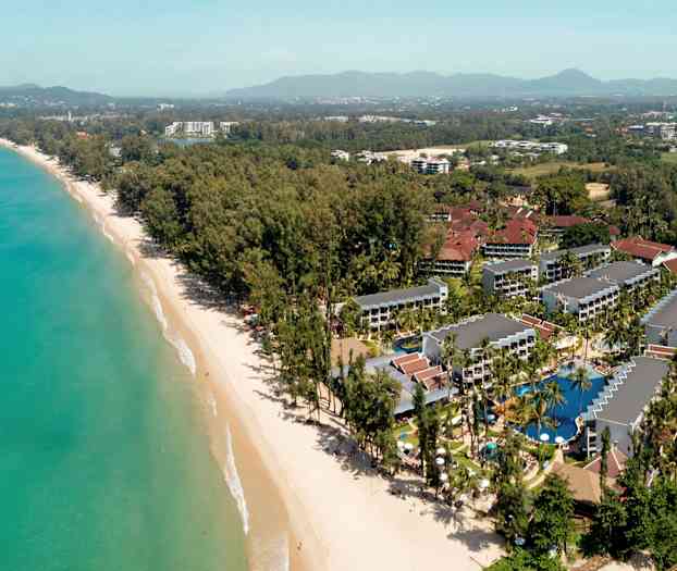 Luftfoto av et feriested ved en strand med omkringliggende trær og bygninger. (AI-generert tekst)