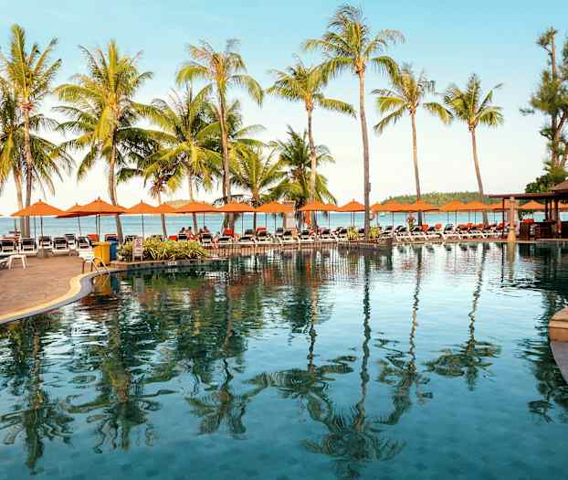 Bassengområde med solsenger, palmer og hav i bakgrunnen. (AI-generert tekst)