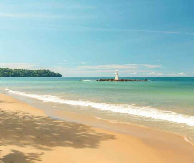 En strand med sand og bølger samt et fyrtårn på en mindre øy. (AI-generert tekst)