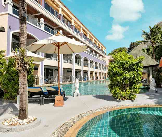 Et svømmebasseng med solsenger og parasoller ved siden av en hotellbygning. (AI-generert tekst)