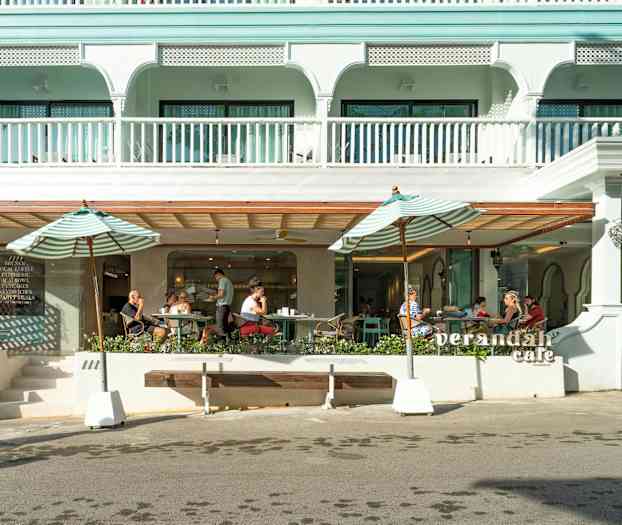 Utendørsbilde av en kafé med parasoller og sitteplasser. (AI-generert tekst)