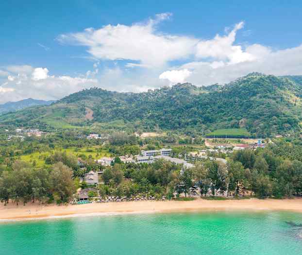 Landskap med en strand, frodige åser og bygninger ved vannet. (AI-generert tekst)