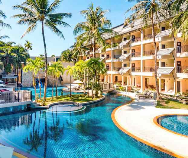 Bilde av et hotellområde med et stort basseng omgitt av palmer og bygninger. (AI-generert tekst)