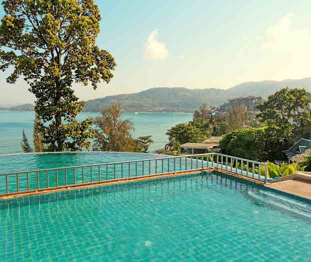 Utsikt over basseng med havet og fjell i bakgrunnen. (AI-generert tekst)