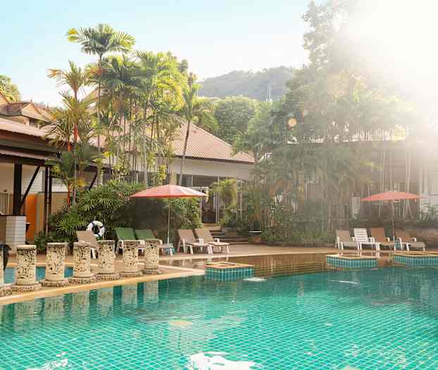 Utendørs basseng med solsenger og parasoller, omgitt av frodige trær. (AI-generert tekst)