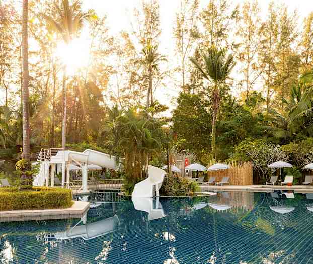 Bassengområde med vannsklie, omgitt av solsenger og frodighet. (AI-generert tekst)