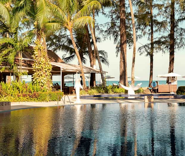 Basseng og tropiske trær med utsikt mot havet. (AI-generert tekst)