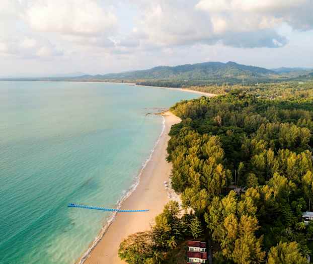 Strand med grønne skogsområder og hav. (AI-generert tekst)