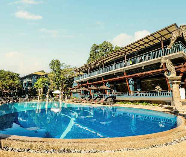 Utendørsbasseng ved et hotell med solsenger og trær rundt. (AI-generert tekst)