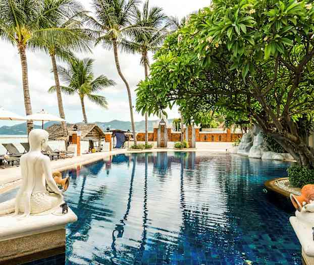 Et basseng omgitt av palmer, statuer og et tropisk miljø. (AI-generert tekst)