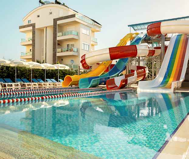 Utendørs basseng med vannsklier og solsenger i nærheten av en leilighetsbygning. (AI-generert tekst)