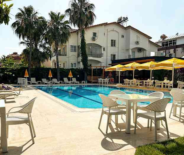 Utendørsbasseng ved et hotell med solsenger og parasoller samt spiseplasser. (AI-generert tekst)