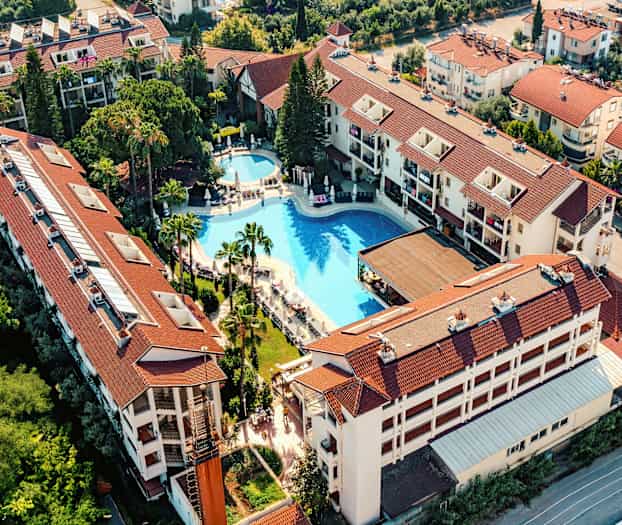 Luftfoto av hotellkompleks med basseng og omkringliggende bygninger. (AI-generert tekst)