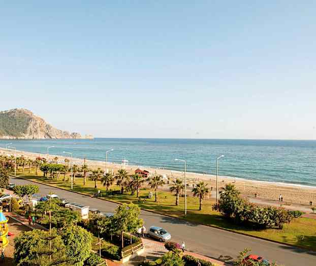 En kystlinje med strand, sjø, og en vei med grøntområder. (AI-generert tekst)