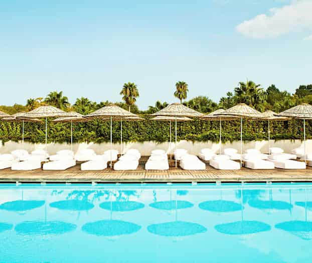 Basseng med solsenger og parasoller i bakgrunnen. (AI-generert tekst)