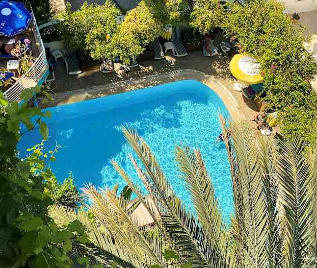 Utsikt over et basseng omgitt av grøntområder og solsenger. (AI-generert tekst)