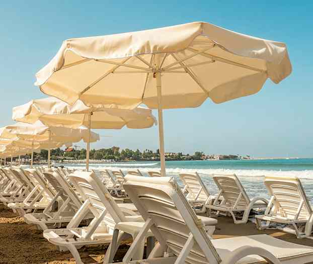 Rad av solsenger og parasoller ved en sandstrand med havutsikt. (AI-generert tekst)