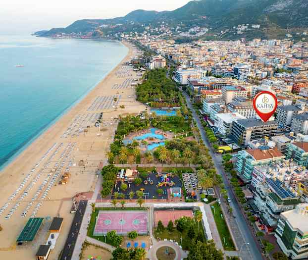 Flyfoto av en strand med solsenger ved siden av bygninger og trær. (AI-generert tekst)