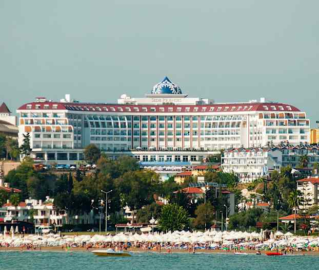 Stor strand med parasoller og hotellbygning i bakgrunnen. (AI-generert tekst)