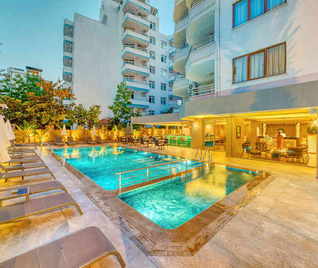 Utendørsbasseng med solsenger og parasoller, omgitt av bygninger. (AI-generert tekst)