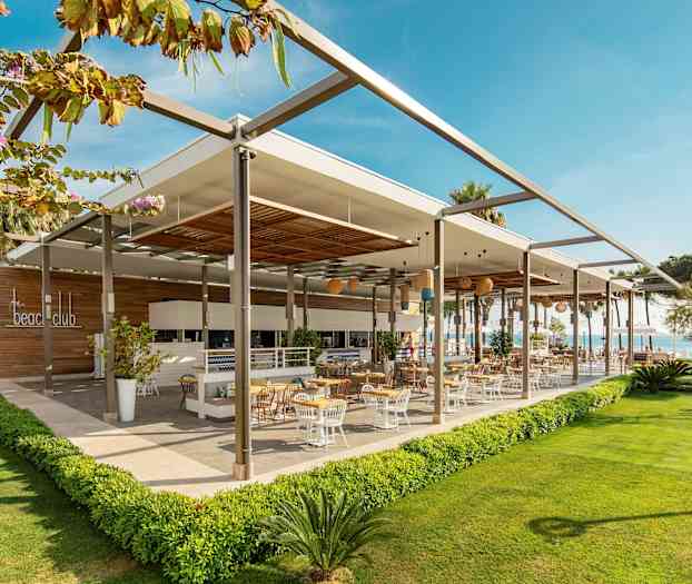 En moderne utendørsrestaurant med uteservering omgitt av grønne områder. (AI-generert tekst)