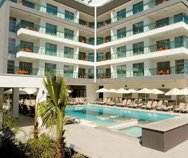 Hotellbygning med moderne balkonger og et basseng omgitt av solsenger og parasoller. (AI-generert tekst)