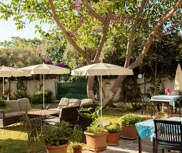 En hage med utemøbler og parasoller. (AI-generert tekst)