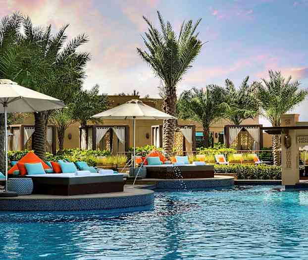 Et svømmebasseng omgitt av solsenger, parasoller og palmer på et feriested. (AI-generert tekst)