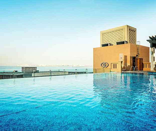 Et infinitybasseng med utsikt over havet og en bygning. (AI-generert tekst)